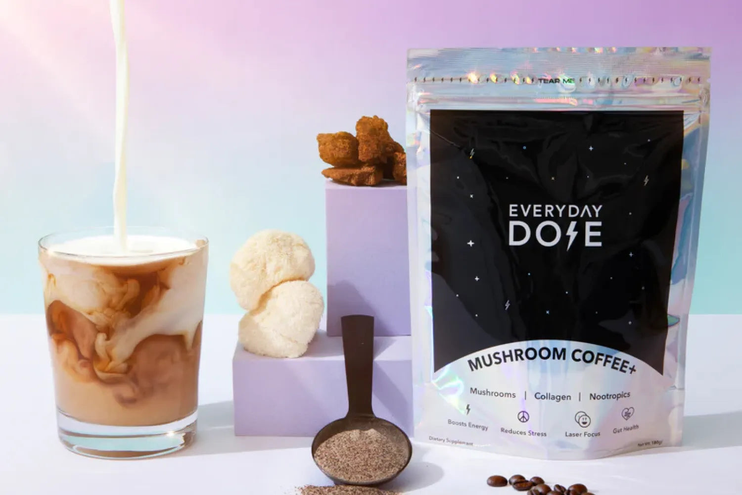Front view of Everyday Dose Mushroom Coffee pouch with powder scoop and milk swirled coffee on pastel background