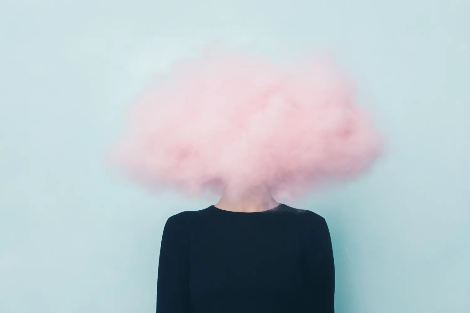 Person with a pink cloud covering their head symbolizing brain fog against a pale blue background