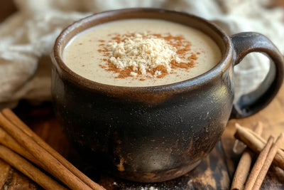 Close-up of Hot Toddy coffee in a rustic dark brown mug topped with grated nutmeg and a dusting of cinnamon, cinnamon sticks on a wooden board
