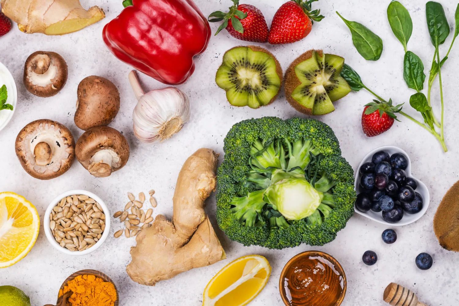 Flat lay of immune-supporting foods including broccoli, ginger, garlic, mushrooms, kiwi, berries, lemon, turmeric, and honey