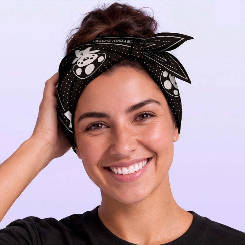 Smiling woman wearing a black patterned headband tied in a bow, featuring white paw print details against a soft lavender background