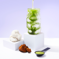 Iced mushroom matcha drink with powder scoop, white powder blocks and chaga mushroom on minimalist display setup