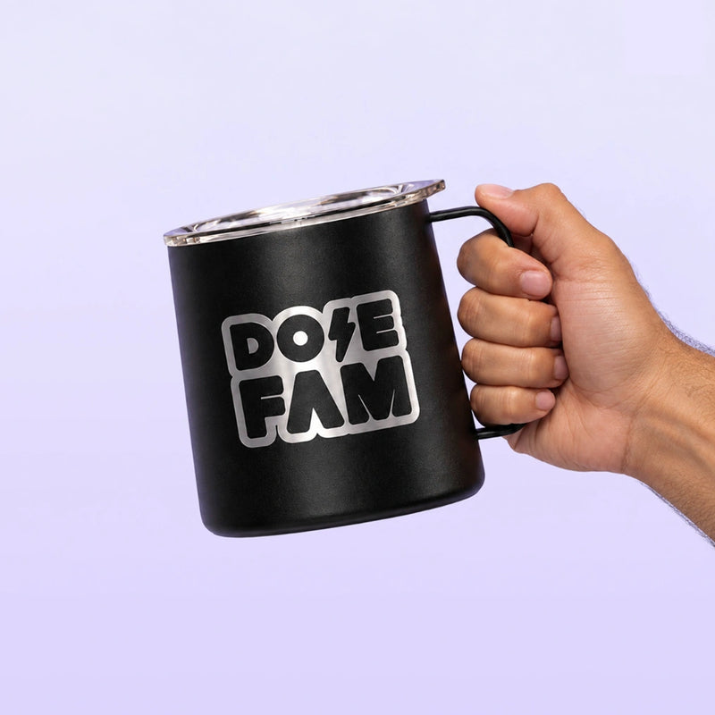 Black handled drink mug with a clear lid and bold white DOPE FAM logo held against a soft lavender background