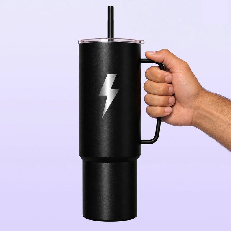 Black insulated tumbler with a side handle clear lid and straw featuring a white lightning bolt against a lavender background