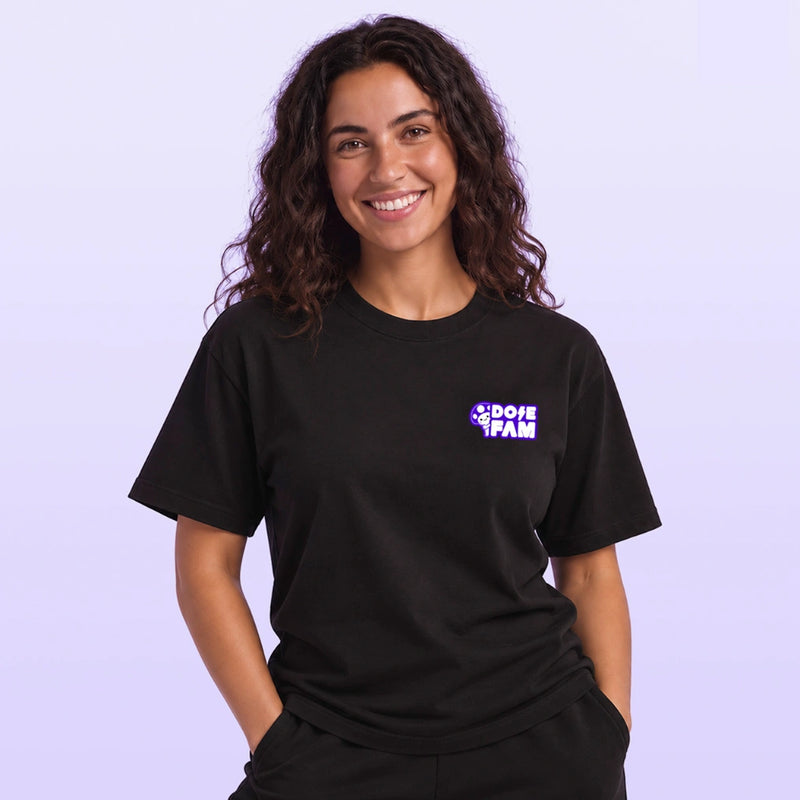 Smiling woman modeling a black short sleeve T shirt with a small purple and white DOPE FAM logo against a lavender background