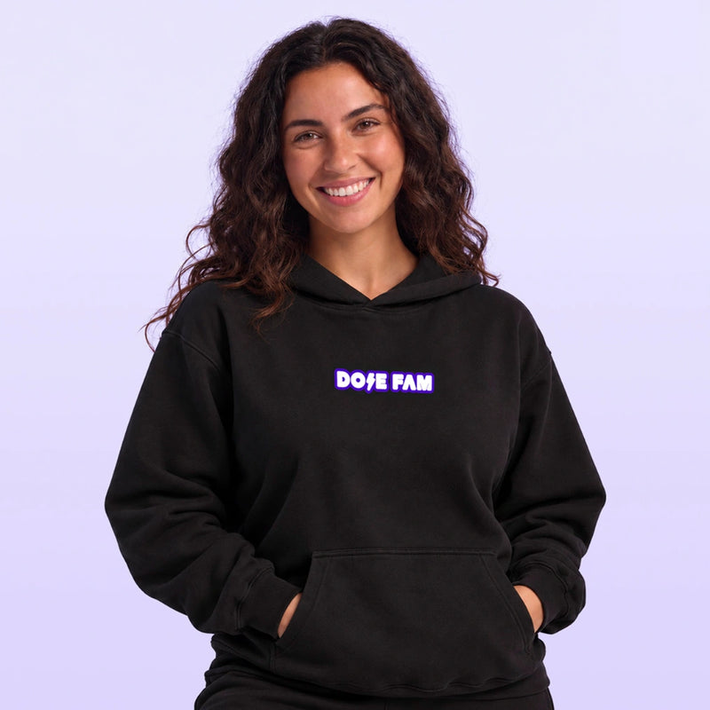 Smiling woman wearing a black pullover hoodie with a purple and white DOPE FAM logo against a lavender background