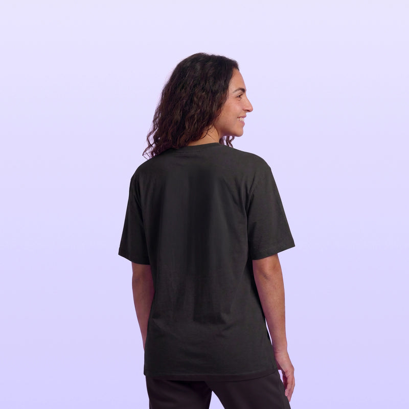 Back and side view of a woman with long hair wearing a plain black short sleeve shirt against a soft lavender background
