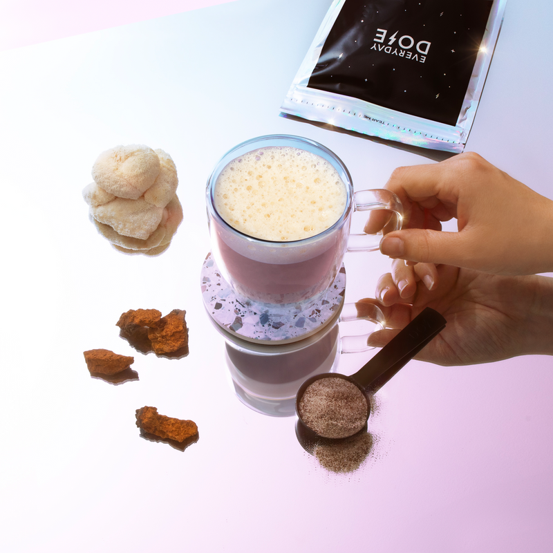 Gift 1 Month of Everyday Dose - frothy mushroom latte in clear glass with adaptogenic powder and ingredients on pink surface