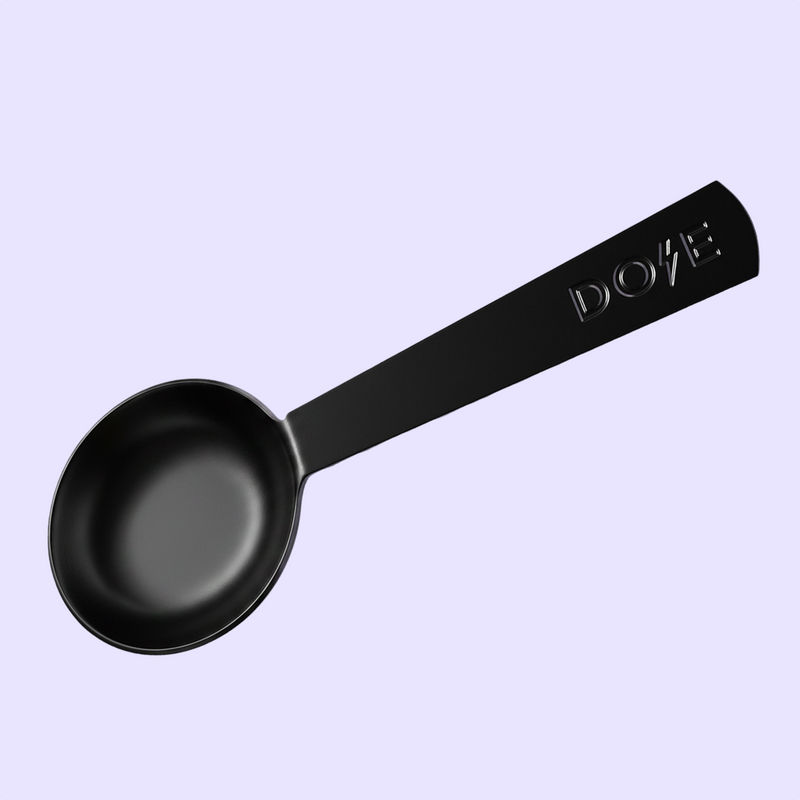 Black ladle with a long handle marked DOVE against a pale lavender background
