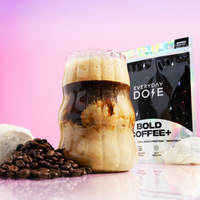 Everyday Dose Bold Coffee+ 30 servings with creamy froth in glass, coffee beans, and product package on pink background